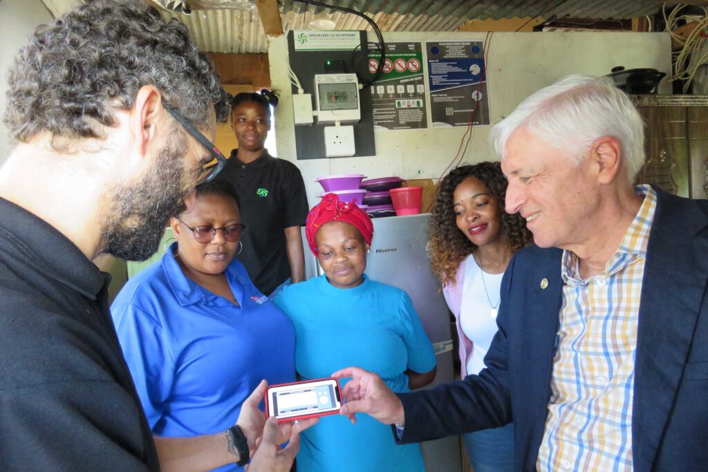  Dmitry Reznichenko a Project Engineer at Specialized Solar Systems (front left) showing Alderman Leon van Wyk, the Executive Mayor of George (front right) how the remotely managed technology works. The onlookers are, from left, Cllr Nosicelo Mbethe (Portfolio Councillor for Electrotechnical Services & Fleet), Phumla Magwebu (Beneficiary) and Cllr Thandiswa Qatana of the George Municipal Council. Standing at the back is Zenande Gubeka from Specialized Solar Systems).