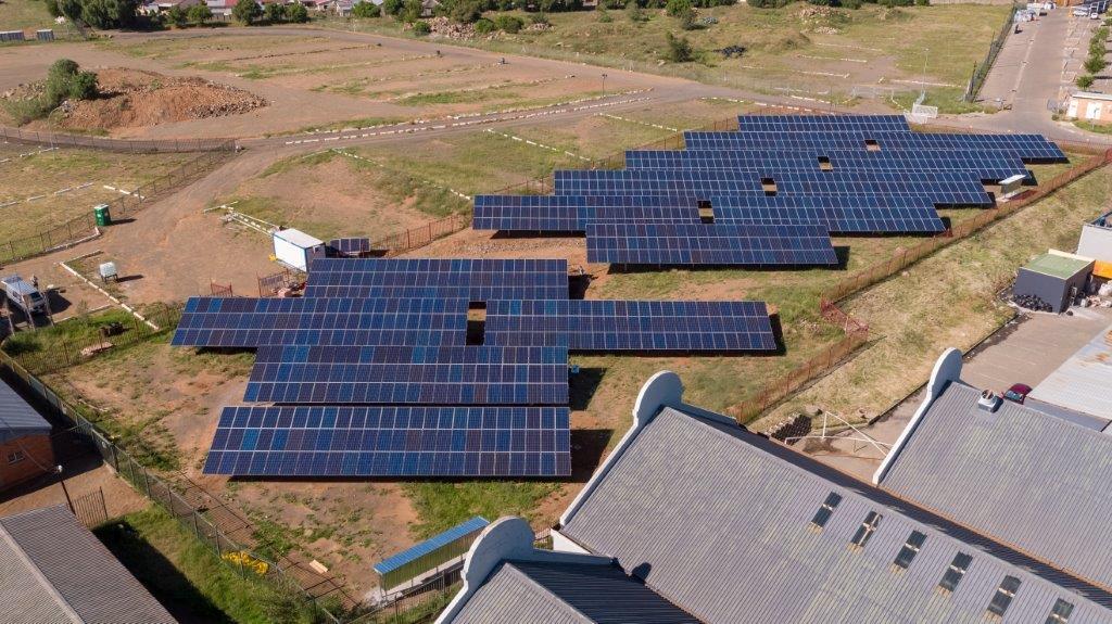 Aerial view of a solar carport with panels shading parked cars.
