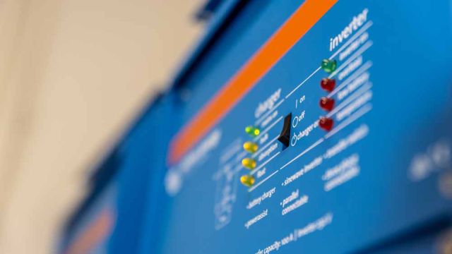 Close-up of a blue Victron solar inverter control panel with LED status indicators and a power switch.
