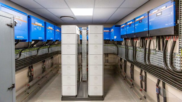 Fully integrated commercial solar plant room featuring central lithium battery racks and wall-mounted Victron inverter-chargers