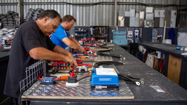 Technicians completing electrical wiring and system assembly on a workshop bench for locally integrated solar energy solutions