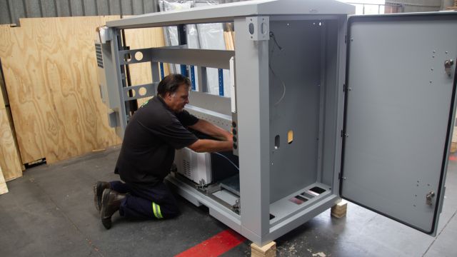 Technician assembling a custom energyPOD solar and storage enclosure at the Specialized Solar Systems manufacturing workshop in George
