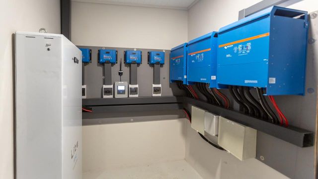 A professionally installed indoor solar energy system featuring Victron inverters, MPPT solar charge controllers, and a lithium battery cabinet.